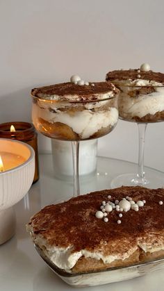 three desserts sitting on top of a table next to a lit candle