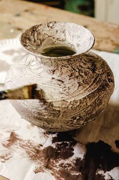 a wooden bowl sitting on top of a table next to a paper plate and paintbrush