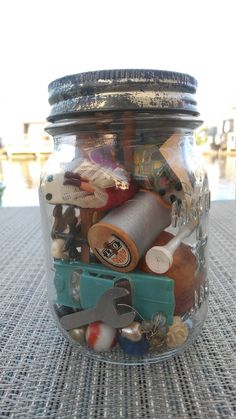 a jar filled with assorted items sitting on top of a table