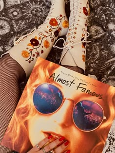 a woman's feet with her hand on the cover of an almost famous book