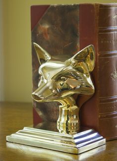 a bookend with a golden fox head on top of it next to a book