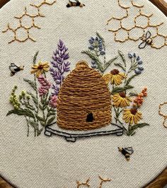 a beehive with flowers and bees on it is embroidered onto a piece of fabric