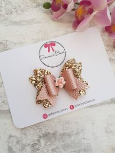 a pair of pink bows with gold sequins on them sitting on top of a card