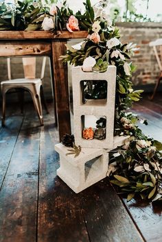 an arrangement of flowers and greenery sits on the floor