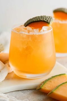 two glasses filled with orange juice and garnished with an avocado on the rim