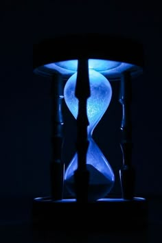 an hourglass sitting on top of a table with blue light coming from it's sides