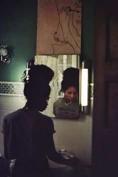 a woman standing in front of a bathroom mirror looking at her reflection on the wall