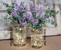 two mason jar vases filled with lavender flowers and fairy lights are sitting next to each other