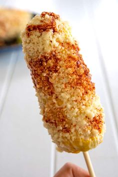 someone is holding up a corn on the cob skewer with toppings