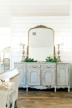 a white dresser with a mirror on top of it next to a tub and chair