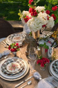 the table is set with plates, silverware and flowers