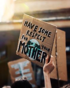 a person holding up a cardboard sign that says have some respect for your mother on it