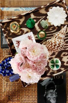 a tray with flowers and other items on it sitting on top of a woven table cloth