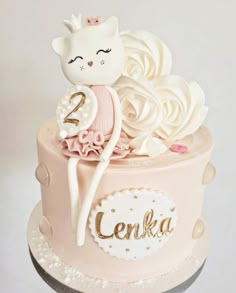 a pink cake with white frosting and a cat on top