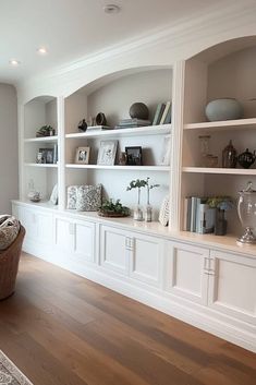 a living room filled with lots of white furniture and bookshelves on top of wooden floors