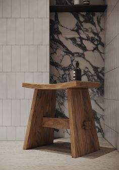 a wooden stool sitting on top of a white tiled floor next to a bottle of wine