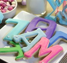 decorated cookies that spell out the word w are on a plate next to bowls of candy