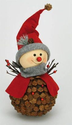 a snowman sitting on top of a pine cone covered in acorns and wearing a red hat