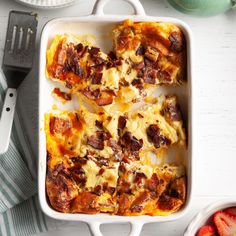 a casserole dish with meat and cheese on it next to some strawberries