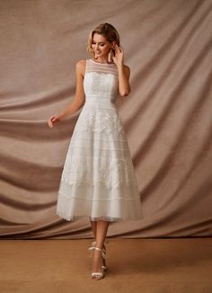 a woman in a white dress is posing for the camera with her hand on her head