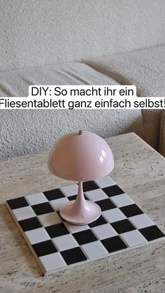 a pink table lamp sitting on top of a black and white checkerboard tile