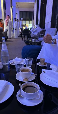 a table topped with plates and cups filled with coffee next to water bottles on top of tables