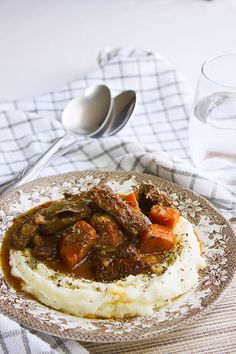 a plate with mashed potatoes, meat and gravy next to a glass of water