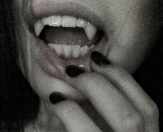 a woman with black and white nail polish holding her hand up to her mouth