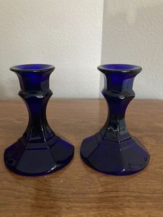 two blue glass candlesticks sitting on top of a wooden table