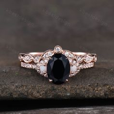 a black and white diamond engagement ring on top of a stone slab with diamonds around it