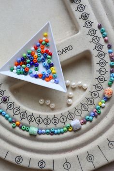 a white plate topped with beads and a triangle shaped object on it's side