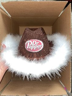 a dr pepper hat in a box with white fur around the bottom and inside it