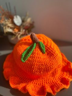 an orange knitted hat with a green leaf on it