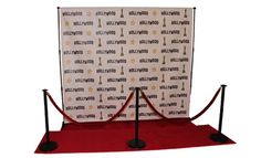 a red carpeted area with two black barriers and a white screen behind it that says hollywood