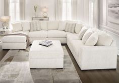 a living room filled with white furniture and decor on top of a hard wood floor