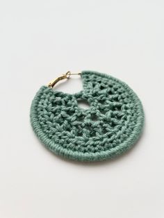 a green crocheted earring on a white surface