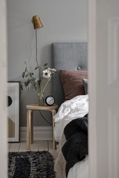 a bed room with a neatly made bed and a plant on the nightstand next to it