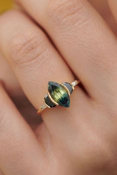 a woman's hand with a gold ring and green tourmaline stone on it