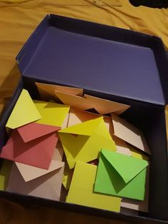 an open box filled with lots of different colored pieces of paper sitting on top of a table