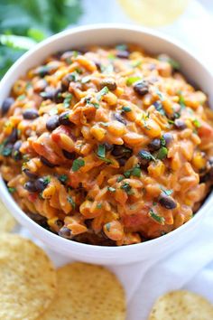 a white bowl filled with black beans and tortilla chips on top of a table