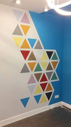 a room with blue walls and white ceiling, painted with colorful geometric shapes on the wall