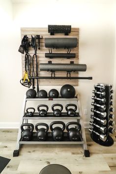 there is a rack with kettles and dumbbells in the room that has a wall mounted gym equipment