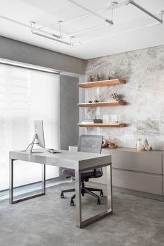 a modern office with marble walls and shelving in the corner, along with an open laptop computer on a desk