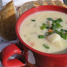 a red bowl filled with soup next to a piece of bread on top of a table