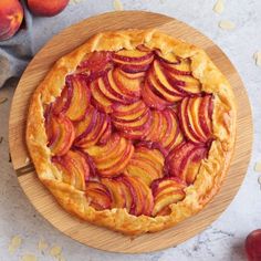 a pie with sliced peaches sitting on top of a wooden plate