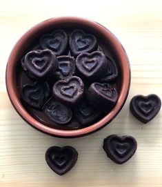 a bowl filled with chocolate hearts on top of a wooden table