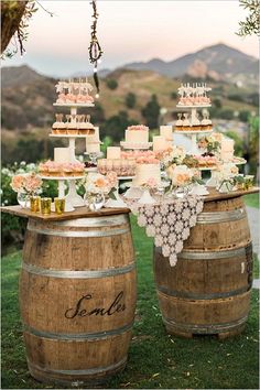 a table topped with cakes and desserts on top of wooden barrels