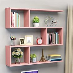 a laptop computer sitting on top of a pink book shelf next to a wall mounted clock