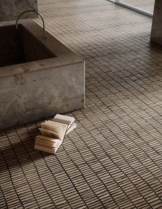 a wooden block laying on the ground in front of a bathtub and floor tile