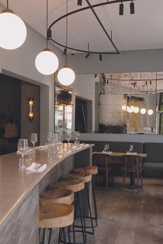 an empty restaurant with wooden bar stools and round lights hanging from the ceiling above